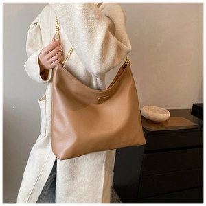 Sac hobo marron en cuir grainé avec bandoulière en chaîne dorée porté par un mannequin