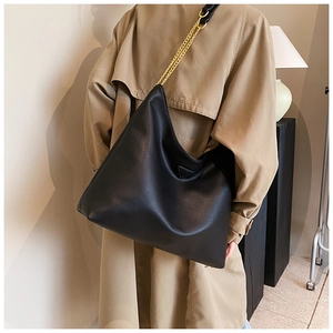 Détail du sac cabas en cuir noir avec chaîne dorée et empiècement triangulaire