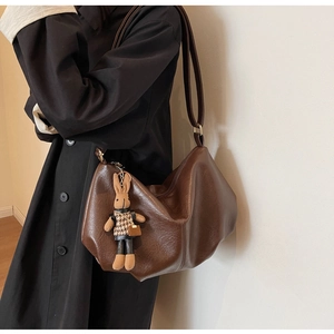 Close-up of caramel leather hobo bag with a cute rabbit charm and houndstooth coat detail