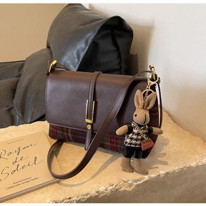 Detail of vintage crossbody bag in brown leather and plaid with a rabbit charm
