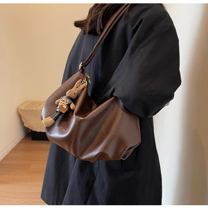 Detailed view of dark brown pleated leather shoulder bag with cute bunny doll charm