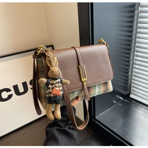 Detail of vintage brown leather and plaid crossbody bag with a cute rabbit pendant accessory