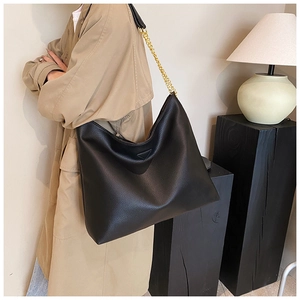 Détail du sac cabas en cuir grainé noir avec chaîne dorée et patch triangulaire décoratif