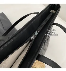 Detail of silver smooth zipper closure and woven lining on black leather tote bag