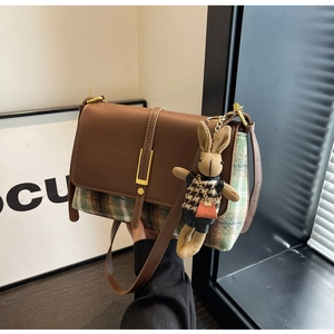 Detail of vintage brown leather handbag with plaid fabric and a cute rabbit charm