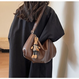 Detail of dark brown pleated hobo bag with a cute rabbit charm on a black coat