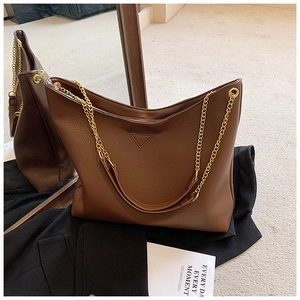 Détail du sac cabas en cuir grainé marron foncé avec plaque triangle et chaîne dorée