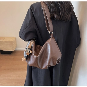 Detail of a brown pleated leather tote bag featuring a cute bunny charm on the strap