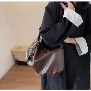 Detail of dark brown pleated hobo bag with a cute plaid bunny charm on the strap