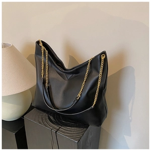 Détail macro du sac seau noir en cuir PU grainé avec bretelles en chaîne dorée et cuir