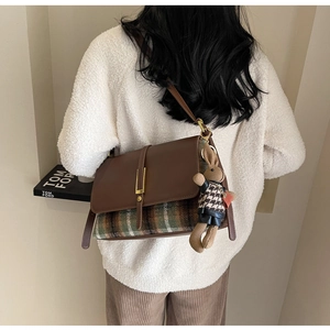 Detail of vintage brown leather crossbody bag with plaid fabric and a cute rabbit charm