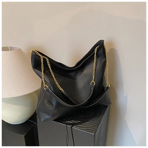 Détail du sac seau en cuir grainé noir avec bandoulière chaîne dorée et coutures épurées