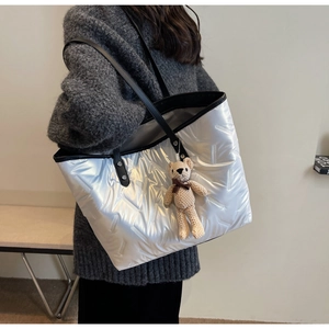 Macro view of silver quilted tote bag with V-shaped stitching and a cute bear charm
