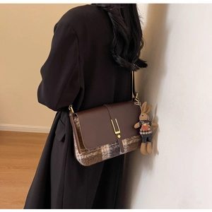 Detail of vintage brown leather and plaid bag with a cute woven bunny pendant accessory