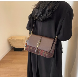 Detail view of vintage brown leather and plaid crossbody bag with gold metal clasp