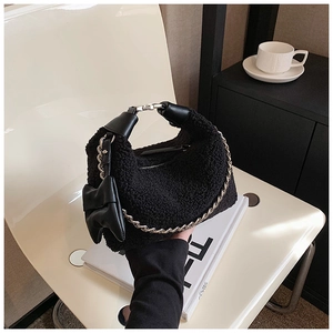Détail du sac à main en peluche noire avec chaîne argentée et nœud en cuir élégant