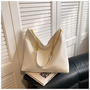 Détail du sac seau blanc texture litchi avec grosse chaîne dorée et ouverture en V