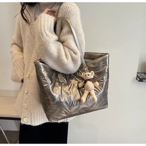 Close-up of metallic quilted tote bag with detachable crochet bear charm and stitching