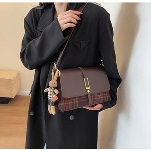Close-up of vintage tartan shoulder bag with brown leather flap and cute bunny charm detail