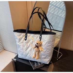 Quilted tote bag detail with black leather handles and cute teddy bear charm accessory
