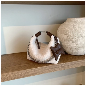 Détail du sac hobo en laine bouclée crème avec anse en cuir et chaîne argentée