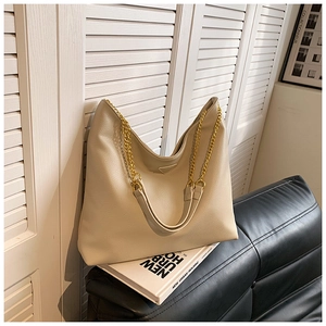Détail du sac seau beige en cuir texturé avec chaîne dorée et boucle triangulaire