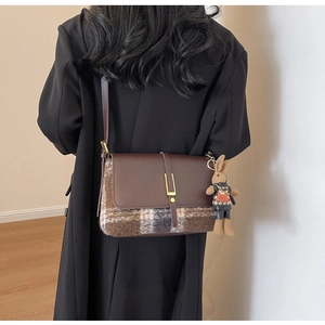 Detail view of vintage checkered shoulder bag featuring a stylish rabbit doll pendant