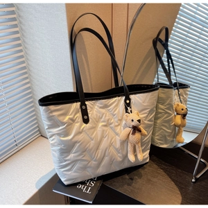Detailed shot of white quilted tote bag with V-pattern stitching and cute bear charm