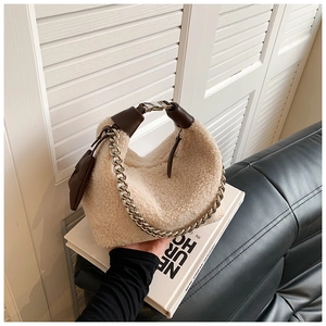 Détail de la texture en laine d'agneau avec chaîne en métal sur un sac beige en peluche