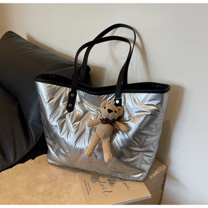 Detail of silver metallic tote bag with quilted rhombus pattern and brown bear charm
