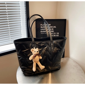 Close-up of black quilted tote bag with V-shaped texture and a cute bear charm