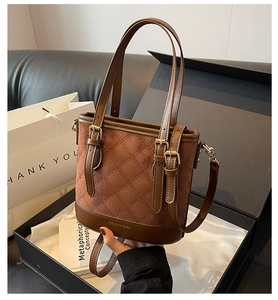 Details einer braunen Wildleder-Beuteltasche mit Steppmuster und goldenen Beschlägen