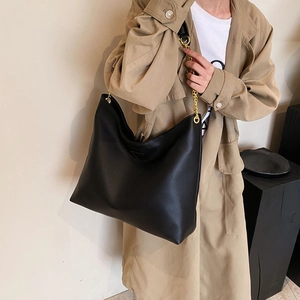 Sac seau minimaliste en cuir noir à grande capacité avec chaîne dorée sur mannequin