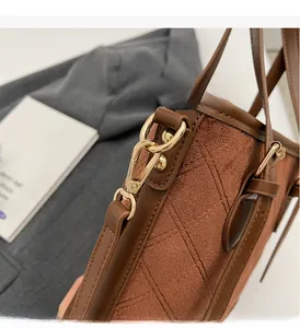 Nahaufnahme der goldenen Beschläge und braunen Wildledernaht der Handtasche