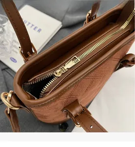 Detail des goldenen Reißverschlusses an der braunen gesteppten Wildledertasche