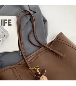 Detail of soft leather tote bag with slim straps and a cute plush bunny charm