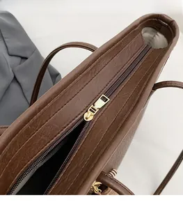 Detail of smooth gold metal zipper closure on large brown faux leather tote bag