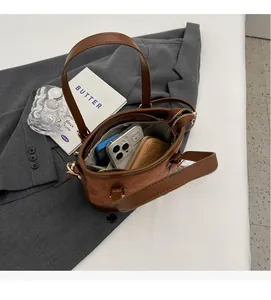 Innenansicht der braunen gesteppten Beuteltasche mit Smartphone und Geldbörse darin