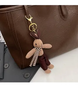 Knitted rabbit charm with scarf and gold hardware on brown leather tote bag