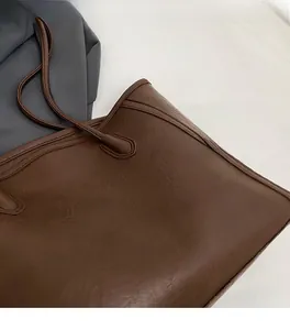 Close-up of the vintage brown faux leather texture and reinforced stitching on a tote bag