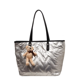 Quilted silver tote bag with black leather handles and a cute beige bear charm detail