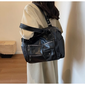Detail view of large capacity black leather travel bag with multi-pocket design on model