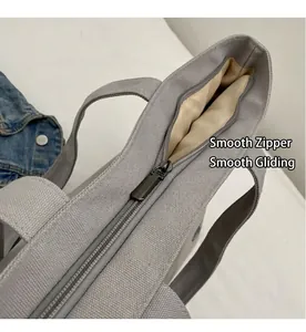 Detalle de una cremallera metálica suave y forro interior de un bolso tote de lona gris