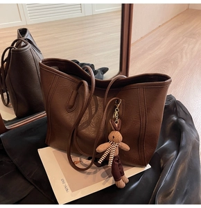 Detail of a brown vintage leather tote bag with a cute rabbit plush charm decoration