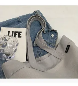 Primer plano de bolsa tote de lona gris claro con asas reforzadas y etiqueta lateral