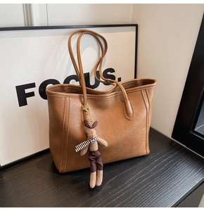 Caramel brown large tote bag detail with fine leather texture and cute rabbit charm