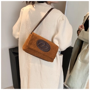 Close-up of caramel fleece shoulder bag with embossed leather M logo patch and strap