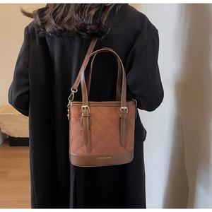Detailaufnahme der braunen Beuteltasche aus mattem Leder mit Steppung und Gold-Hardware