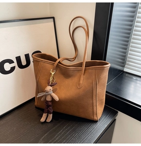 Detailed view of a brown tote bag featuring fine texture and a cute rabbit charm