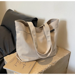 Detalle de costura de bolso tote de lona con etiqueta de marca en base de piedra